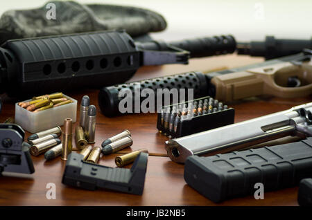 Nahaufnahme von einer Schrotflinte und einem Revolver, Patronengürtel mit Kugeln auf Holztisch. Stockfoto