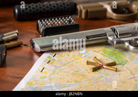 Nahaufnahme von einer Schrotflinte und einem Revolver, Patronengürtel mit Kugeln auf einer Karte auf Holztisch. Stockfoto