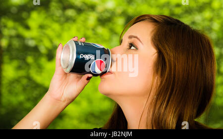 Quito, Ecuador - 6. Mai 2017: Hübsche junge Frau trinkt Pepsi in Grün der Hintergrund jedoch unscharf. Stockfoto