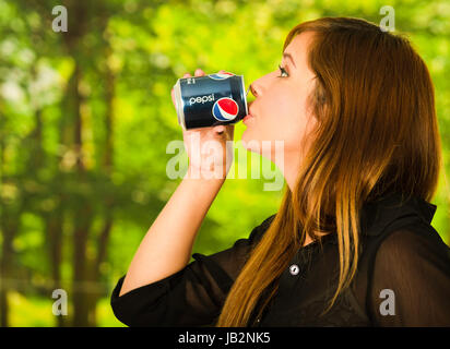 Quito, Ecuador - 6. Mai 2017: Hübsche junge Frau trinkt Pepsi in Grün der Hintergrund jedoch unscharf. Stockfoto