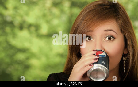 Quito, Ecuador - 6. Mai 2017: Hübsche junge Frau trinkt Pepsi in Grün der Hintergrund jedoch unscharf. Stockfoto