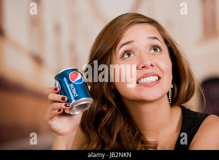 Quito, Ecuador - 6. Mai 2017: Lächelnde junge Frau hält eine Pepsi in unscharfen Stadt Hintergrund. Stockfoto