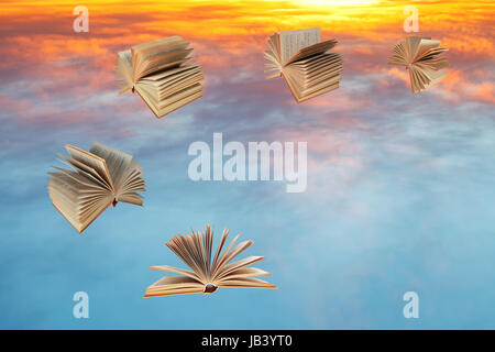 Bücher fliegen über blaue und gelbe Sonnenuntergang Wolken Stockfoto