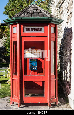 Arrowtown, New Zealand - 16. März 2017: Nahaufnahme des historischen aber aktiv rote Telefonzelle in der Stadt. Holzkonstruktion mit blauen Telefon. Einige grüne Stockfoto