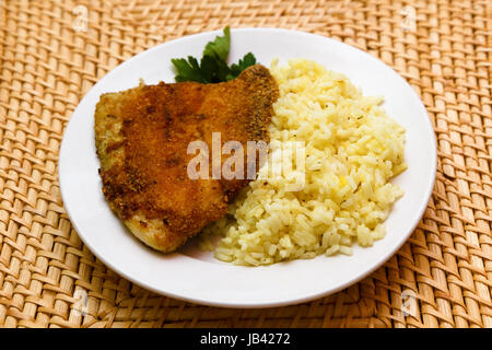 Gebratene panierte Tilapia, serviert mit Reis und Kräutern Stockfoto