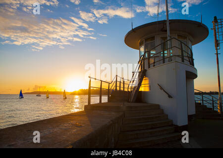 Mount Batten Pier vom Meer Ozean abgehen in Ferne am goldenen Sonnenuntergang segeln Yachten in Plymouth Sound, Devon, England, UK Stockfoto