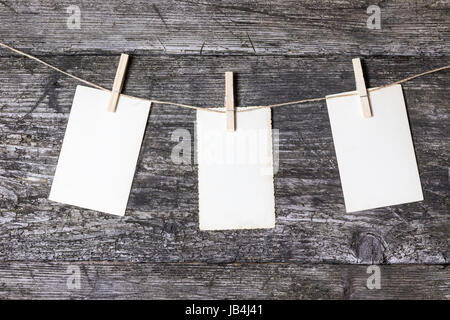 Drei alte leere Fotos hängen die Leine mit der Wäsche-Pins. Die Fotos sind im Bogen hängen. Leere Fotos sind bereit für Ihren Text. Stockfoto