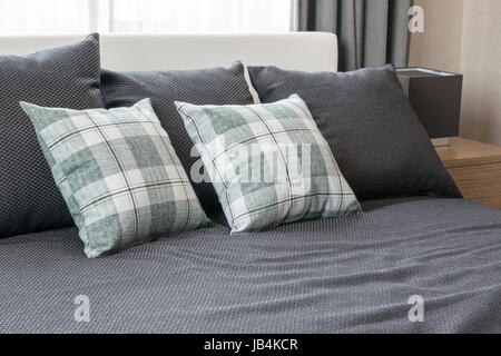 Schlafzimmer-Innenarchitektur mit aufgegebenen grüne Kissen auf graue Bett und dekorative Tischleuchte. Stockfoto