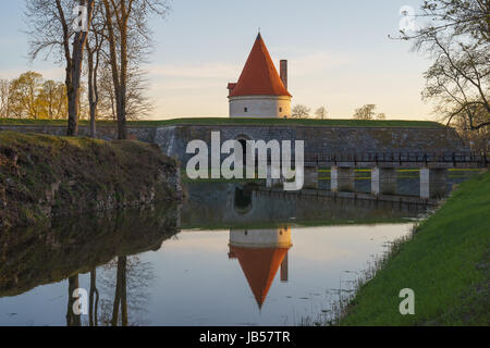 Kuressaare Burgturm mit Brücke über den Graben im Abendlicht. Wasser mit Reflektionen im Vordergrund. Stockfoto