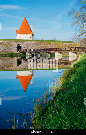 Kuressaare Burgturm mit Brücke über den Graben gegen blauen Himmel. Wasser mit Reflektionen im Vordergrund. Stockfoto