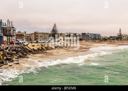 Wellen, Steinen an der Küste mit Häusern im Hintergrund, deutschen Kolonialstadt Swakopmund, Namibia Stockfoto