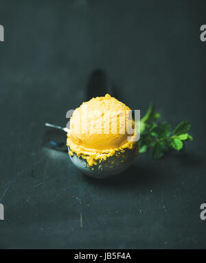 Mango-Sorbet Eisportionierer Scooper über hölzerne Hintergrund Stockfoto