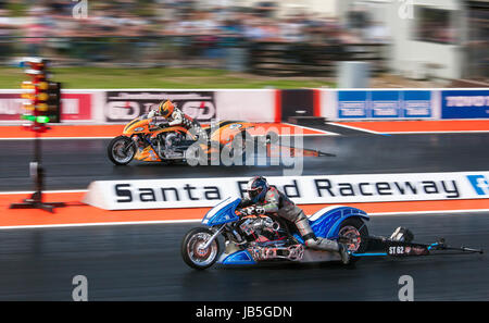 Super Twin Drag-Racing auf dem Santa Pod Raceway. Römische Sixta Nitro V60 Beifahrerseite V Ronny Selbstvergötterung Zodiac Harley jenseits. Stockfoto