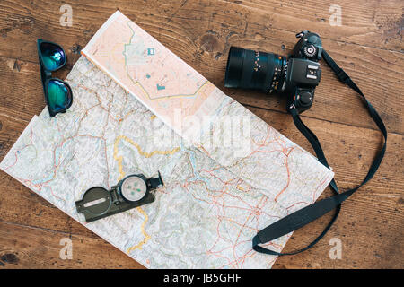 Roadtrip, Exploration Zubehör und Ausrüstungen zur Festlegung auf einer Karte auf einen hölzernen Tisch. Sonnenbrille, Kompass, Kamera und Karte Stockfoto