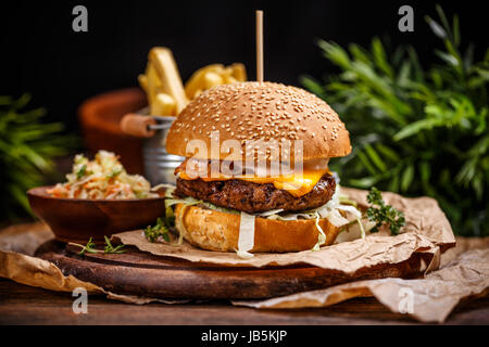 Köstliche Cheeseburger serviert ein knuspriges goldenen Brötchen auf einem Papier Handwerk Stockfoto