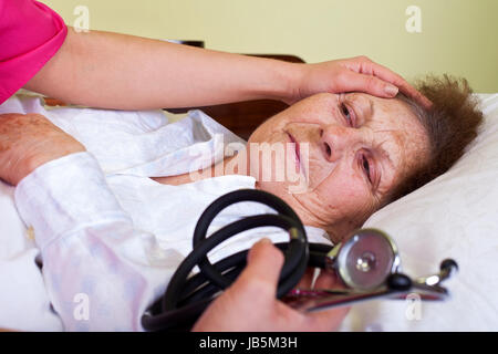 Bild von eine kranke ältere Frau mit ihrem Betreuer halten ein Stethoskop Stockfoto