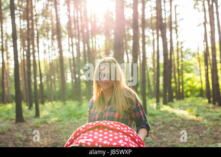 Mutter und schieben Sie einen Kinderwagen im Park spazieren. Stockfoto