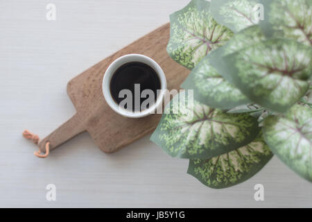 Kaffee tropft in Keramik Vintage Tasse mit Kunstpflanze Stockfoto