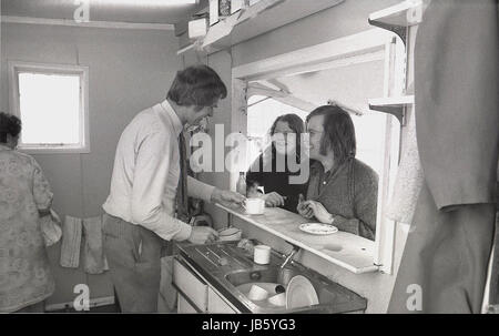 1973, historisches Bild von zwei Kunden, die draußen unter dem Baldachin am Schalter des berühmten Blackheath Tea Hut stehen und mit dem männlichen Kellner am Waschbecken plaudern. Die einfache Snackbar war ein bekannter Raststopp für Leute, die auf der A2 Straße in Greenwich, South London, SE3 unterwegs waren. Stockfoto