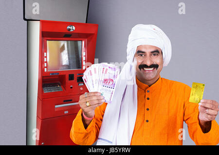 1 Indischen ländlichen Bauern Mann mit Geldautomat und Anzeigen Debitkarte mit Rupien Notizen.- Geldautomaten Geld abheben Konzept Stockfoto