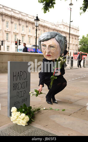 Ein Protest organisiert durch die globale Kampagne Bewegung Avaaz auf Whitehall in London, einer lebensgroßen Riesen-köpfigen Marionette von Theresa Mai verlassen Blumen an einen Grabstein mit der Aufschrift schwer Brexit RIP, wie ihre Zukunft als Premierminister und Führer der konservativen offen in Frage gestellt wurde, nachdem ihre Entscheidung, eine Snap-Wahl katastrophal zu halten ging nach hinten los. Stockfoto