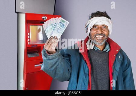 1 Indischen ländlichen Mann mit Geldautomat und zeigen Rupien Notizen.- Geldautomaten Geld abheben Konzept Stockfoto