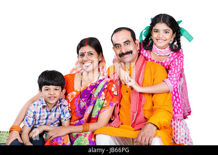 Happy Indischen ländlichen Familie - Eltern mit 2 Kindern sitzen auf Charpai zusammen auf weißem Hintergrund Stockfoto