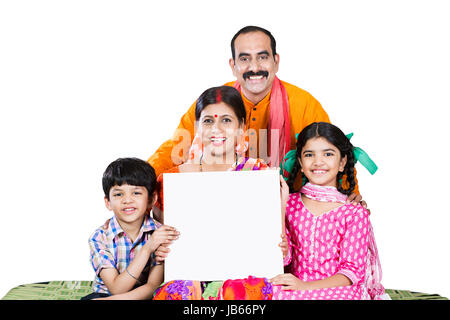 Happy Indischen ländlichen Familie - Eltern mit 2 Kindern sitzen auf Babybett zusammen und zeigt, White Board Stockfoto