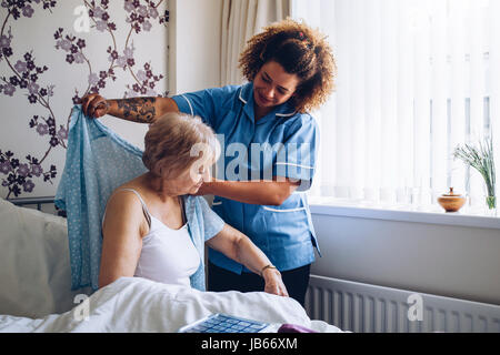 Nach Hause Betreuer helfen, eine ältere Frau in ihrem Schlafzimmer anziehen. Stockfoto