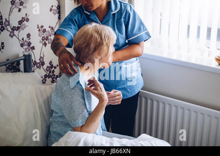 Nach Hause Betreuer helfen, eine ältere Frau in ihrem Schlafzimmer anziehen. Stockfoto