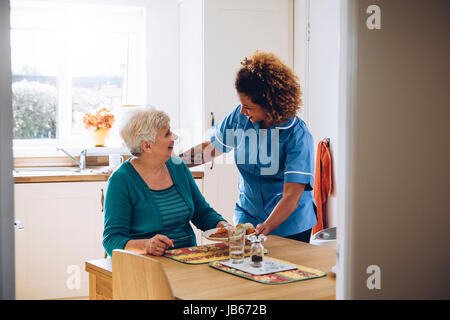 Care Arbeitnehmer geben einer alten Dame ihr Abendessen in ihrem Haus. Stockfoto