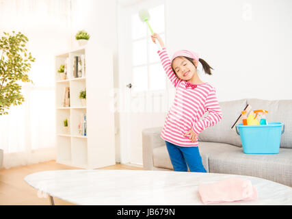 Sauberes kleines Mädchen Spaß beim Frühjahrsputz. Lustige Kinder Reinigung tragen rosa Top Gesang in Besen. Hausarbeit und Haushalt-Konzept. Stockfoto