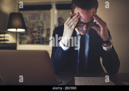 Nachdenklich Geschäftsmann am Schreibtisch und arbeitet mit den Dokumenten in der Nacht. Stockfoto