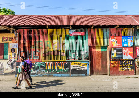 Livingston, Guatemala - 31. August 2016: Mädchen vorbei an bunt bemalte Wände in der Straße in der karibischen Stadt Livingston Stockfoto