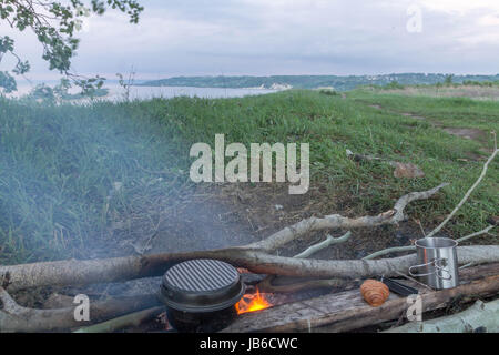 Kochen auf dem Scheiterhaufen. Picknick am Ufer Flusses. Stockfoto