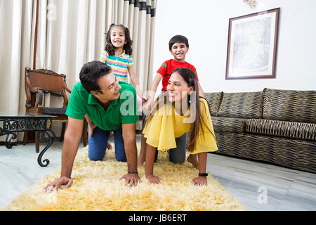 4 Leute, die zu Hause junge Familie mädchen kinder Eltern reiten sitzt lächelnd Stockfoto