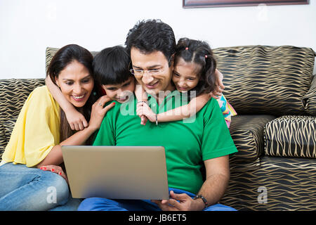 4 Leute, die zu Hause junge Familie mädchen kinder laptop Eltern sitzen arbeiten Stockfoto