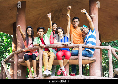 Gerne indische Gruppe jugendliche Jungen und Mädchen sitzen Holz Bank und hob die Hand Jubel Stockfoto