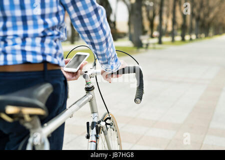 Älterer Mann mit Smartphone und Fahrrad in der Stadt. Stockfoto