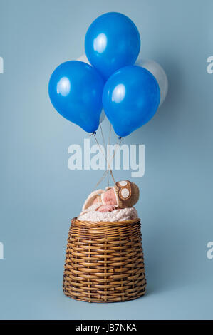 Schlafen neun Tage alten neugeborenen Jungen tragen eine Cabriohaube und schlafen in einem vorgeben Heißluftballon. Stockfoto