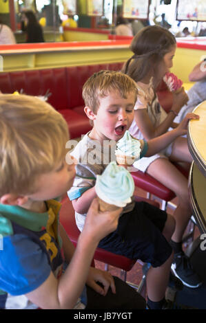 Dh junge Kinder Kinder essen Eis Kegel junge lecken Eis Scarborough Cafe Stockfoto