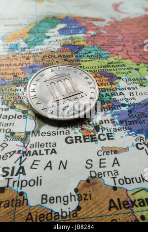 Griechische Münze auf Welt-Karte-Stillleben Stockfoto