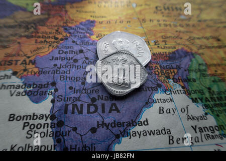 Indische Rupie-Münzen auf Welt Karte Stillleben Stockfoto