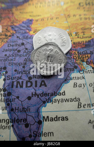Indische Rupie-Münzen auf Welt Karte Stillleben Stockfoto