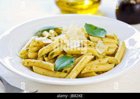 Penne in Pesto-Sauce mit geriebenem Parmesan obenauf Stockfoto