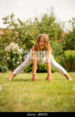 Sport auf Rasen - lächelnd kleines Kind trainieren im Freien im Garten Stockfoto