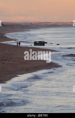 Paare nehmen ihre abendlichen Spaziergang, über Donmouth, bei Sonnenuntergang in der Nähe einer zweiten Weltkrieg "Pill-Box". Aberdeen, Schottland. Februar 2017. Stockfoto