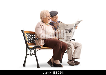 Freudige älteres Paar auf einer Bank sitzt und liest eine Zeitung zusammen isoliert auf weißem Hintergrund Stockfoto