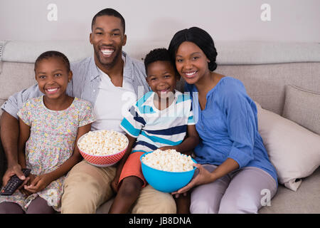 Fröhliche Familie mit Popcorn Schalen Standortwahl zu Hause auf sofa Stockfoto