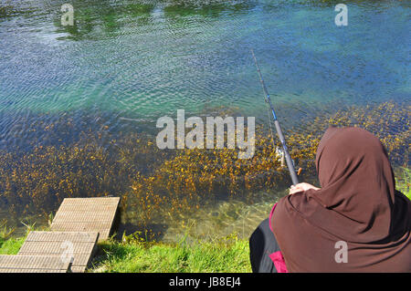 Verschleierte Frau Angeln am See Garten Stockfoto